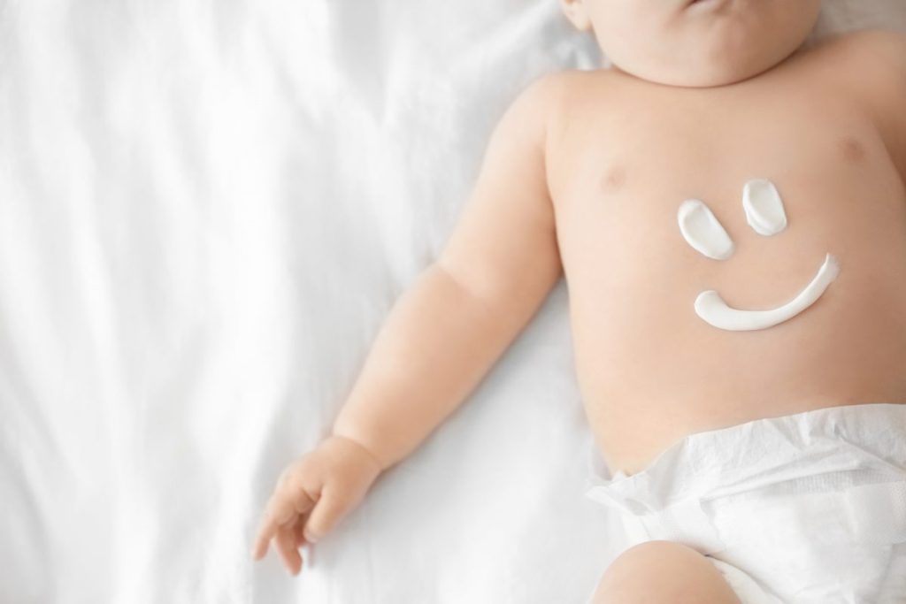 Cute baby with body cream on tummy