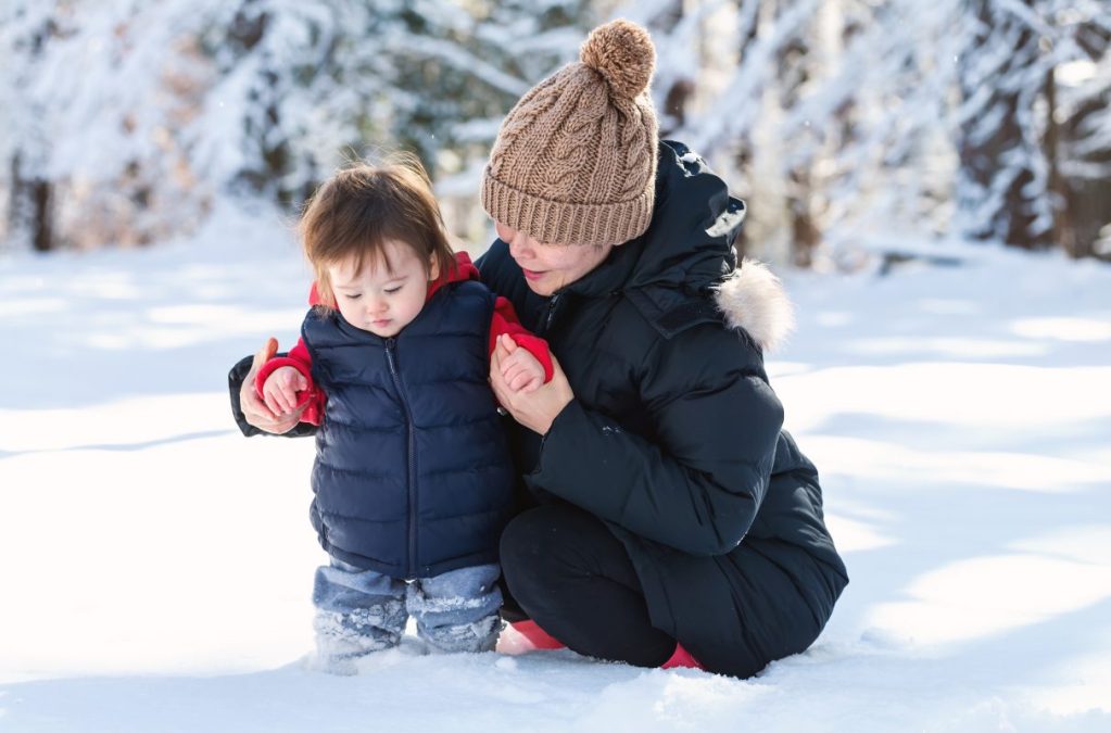 Toddler playing in snow with his mother. Children's diets need lots of nutrients in the winter.