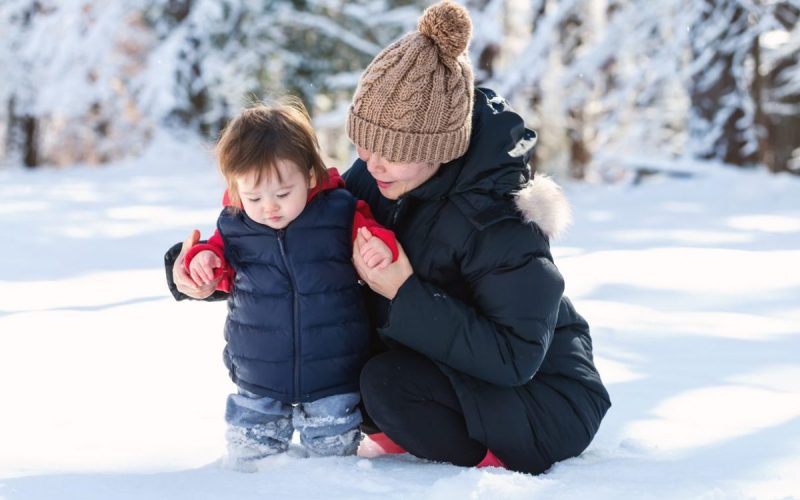 Toddler playing in snow with his mother. Children's diets need lots of nutrients in the winter.